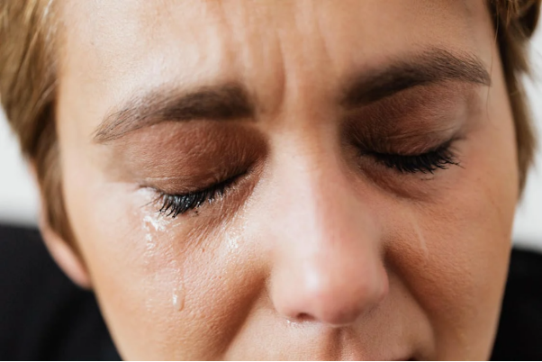 Close-up of a woman’s face with tears streaming down her cheeks.